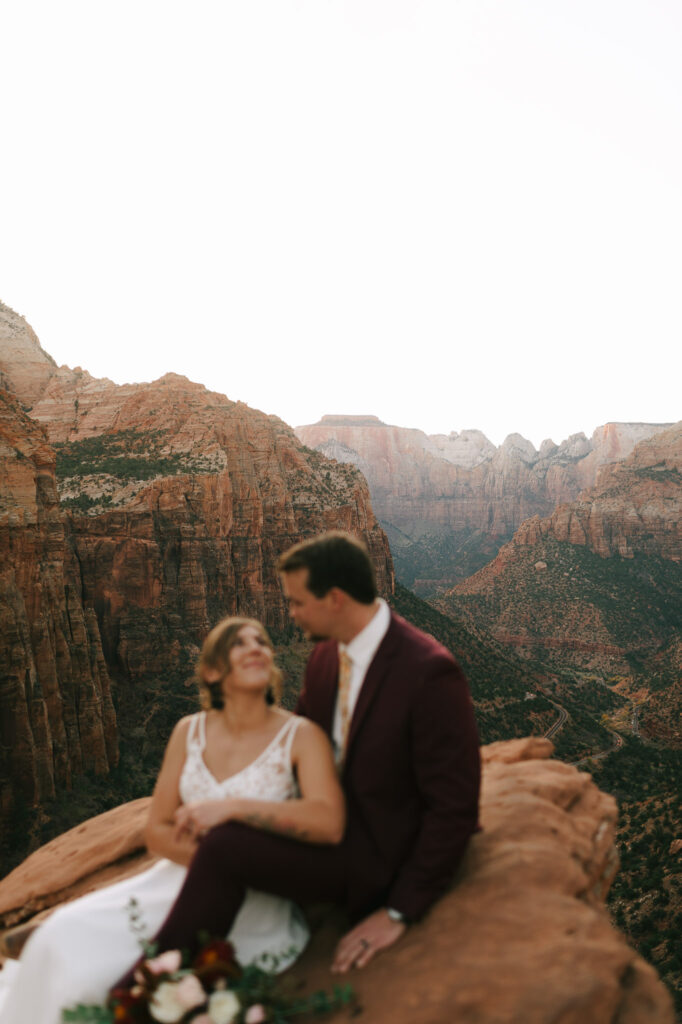 Nicole leans on Kaleb as they sit on a cliff in Zion National Park