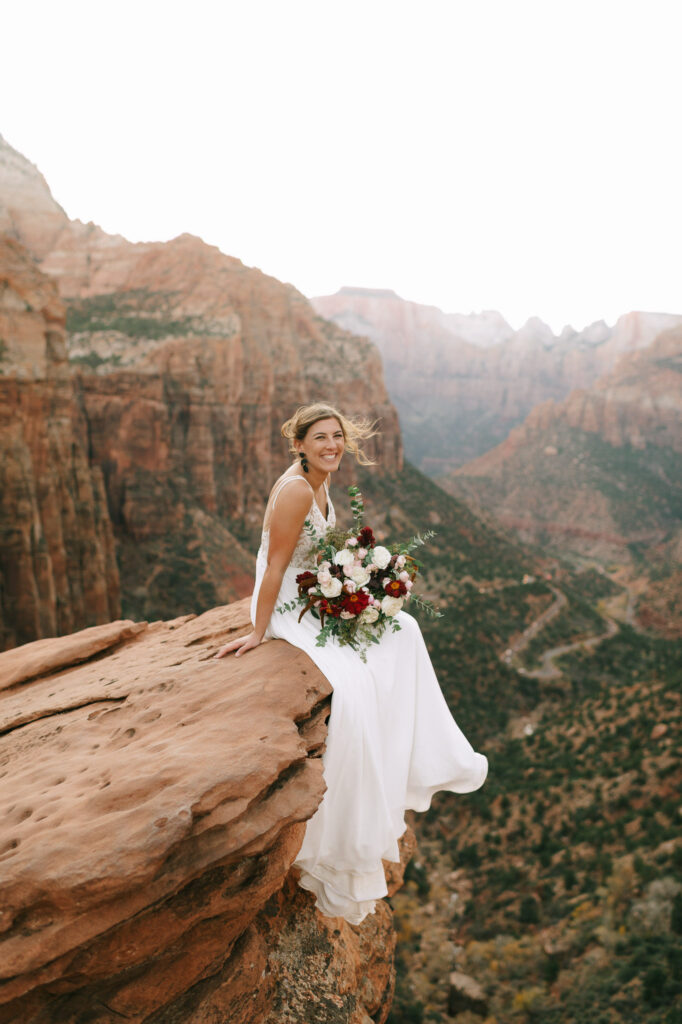 Nicole sits on the side of a cliff over the canyon at Zion National Park