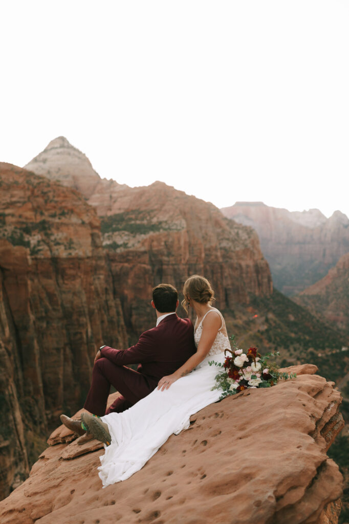 Nicole and Kaleb look out over the canyon as they sit on a cliff in Zion National Park