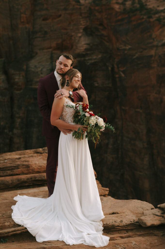 The couple embraces on a cliffside in Zion National Park