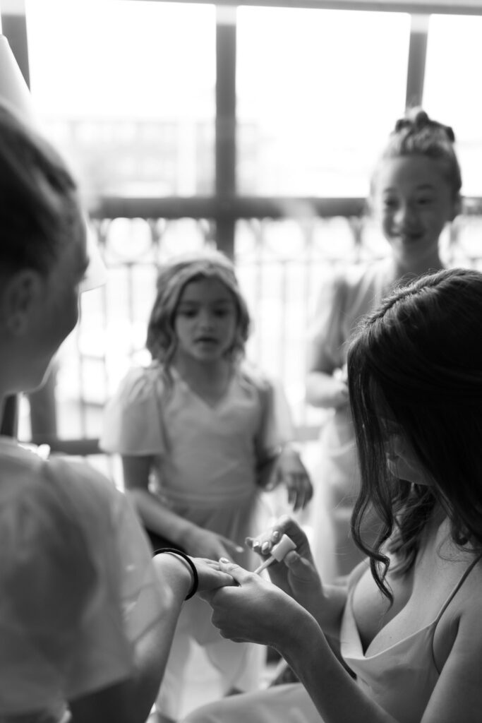 A bridesmaid helps the flower girls with their nails