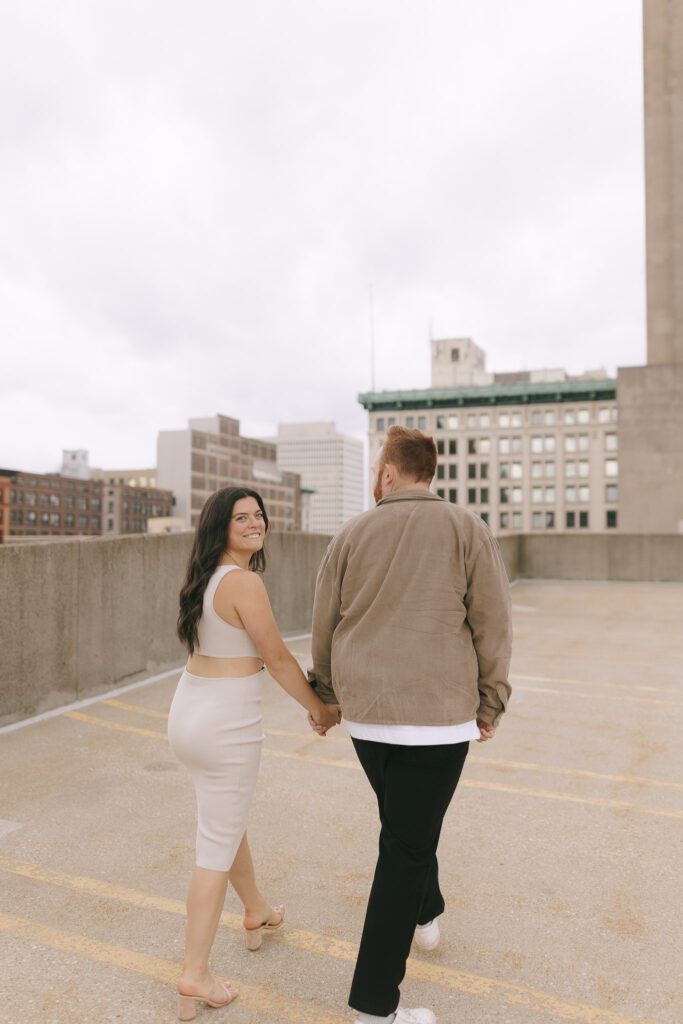 Couple walks on rooftop for their Downtown Toledo engagement photos