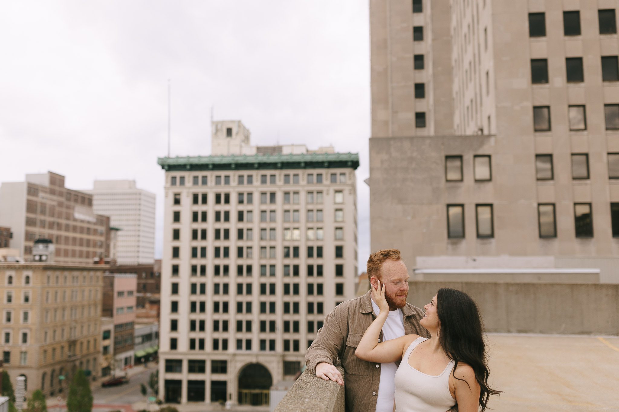 Couple stands on rooftop for their Downtown Toledo engagement photos