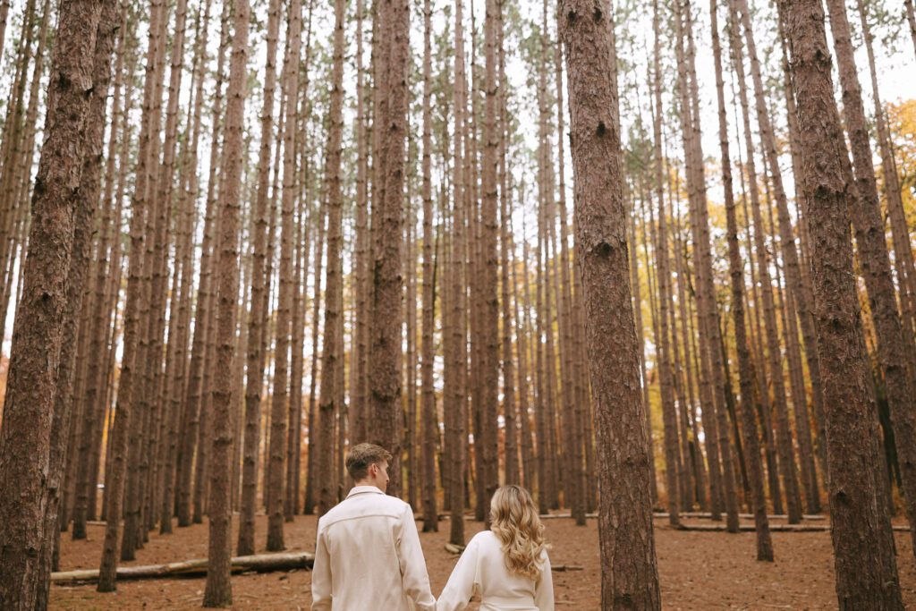 Sophia and Brad walk through an oak grove 