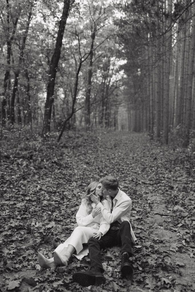 Sophia and Brad sit in the leaves and embrace