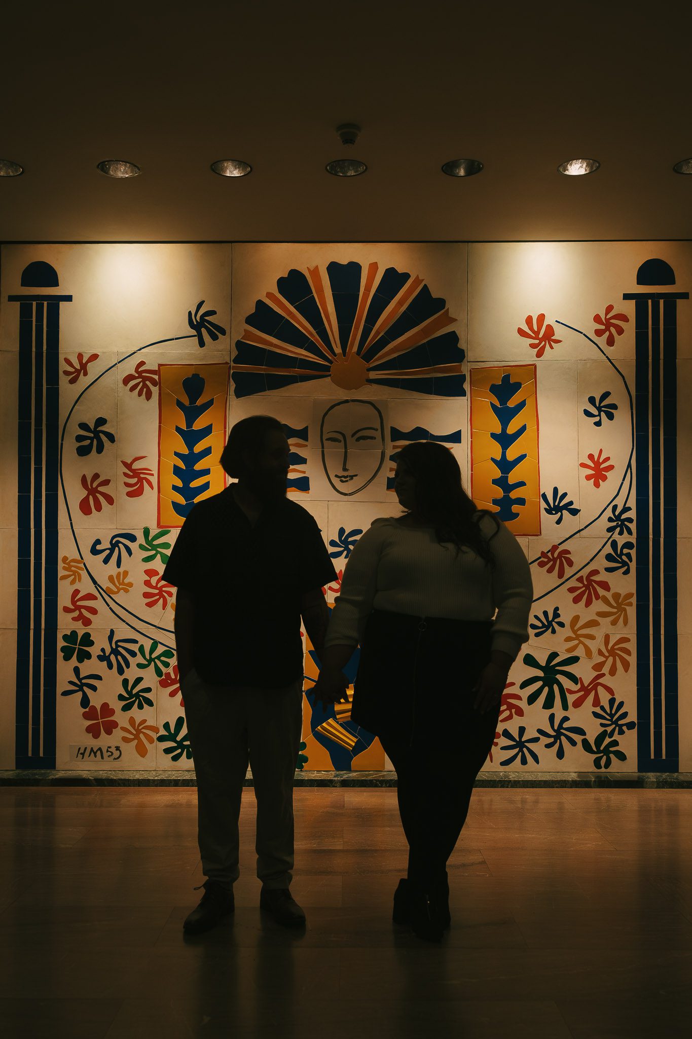Adam and Bethany stand in front of a mural at the museum