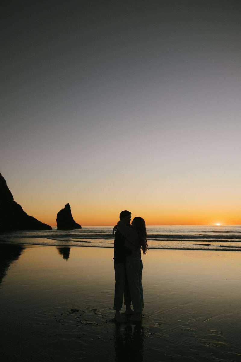 Jason and Leah embrace on the beach at sunset