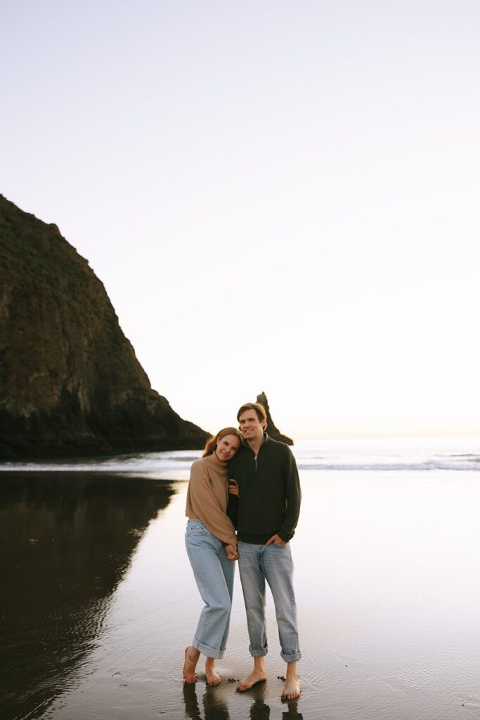 Jason and Leah stand on the beach at sunset