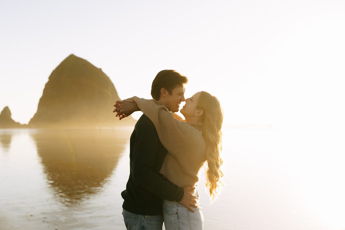 J&L embrace on the beach for their engagement photos