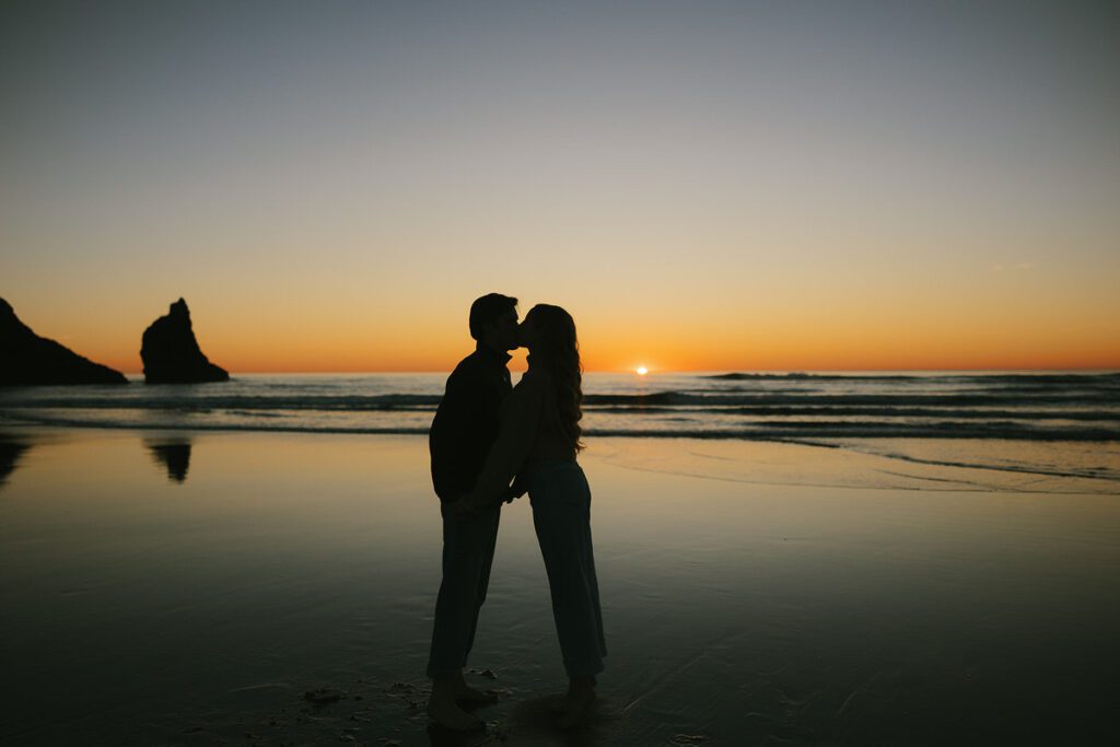 Jason and Leah kiss on the beach at sunset