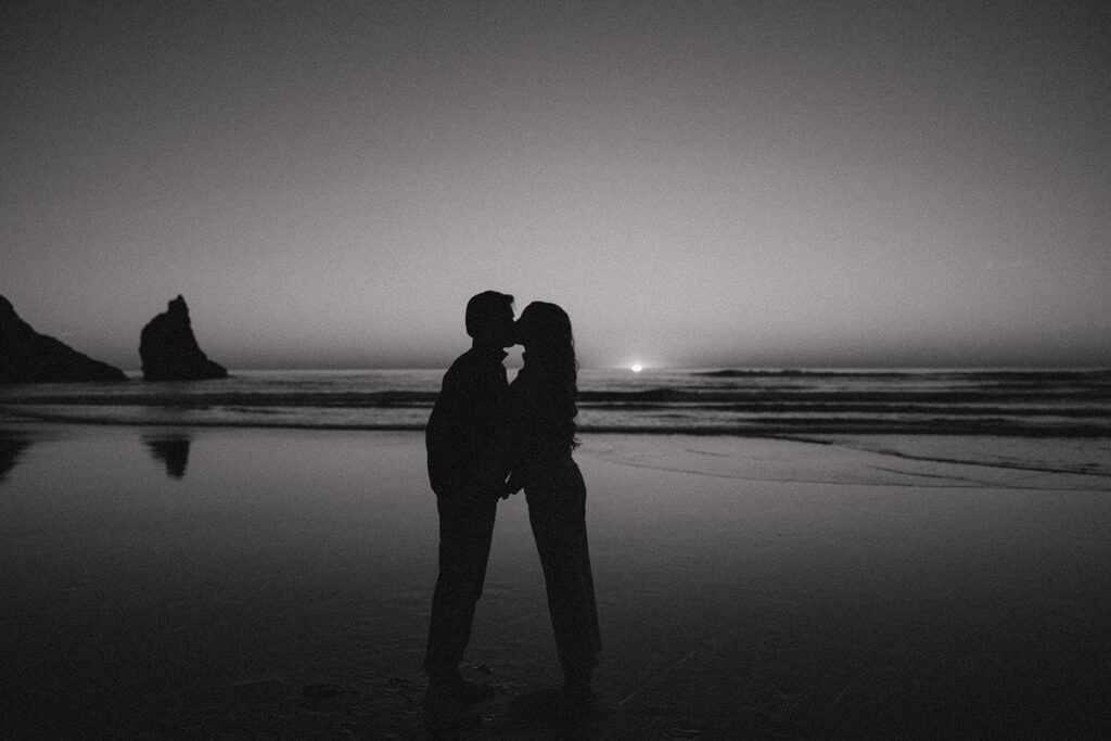 Jason and Leah kiss on the beach at sunset