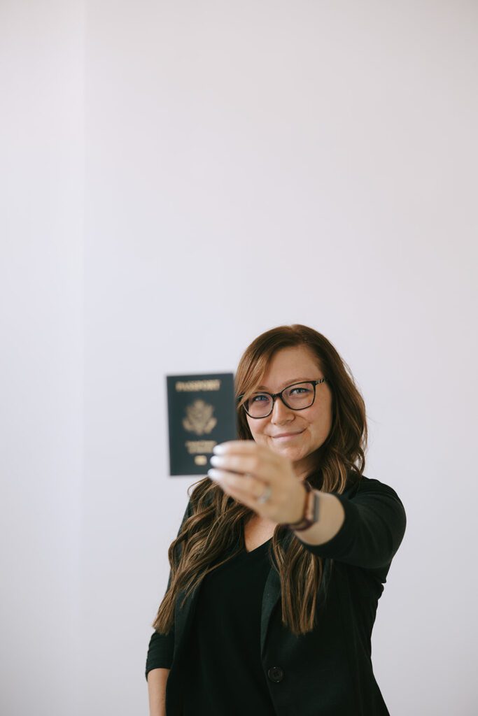 Katie holds up her passport as a destination wedding travel agent