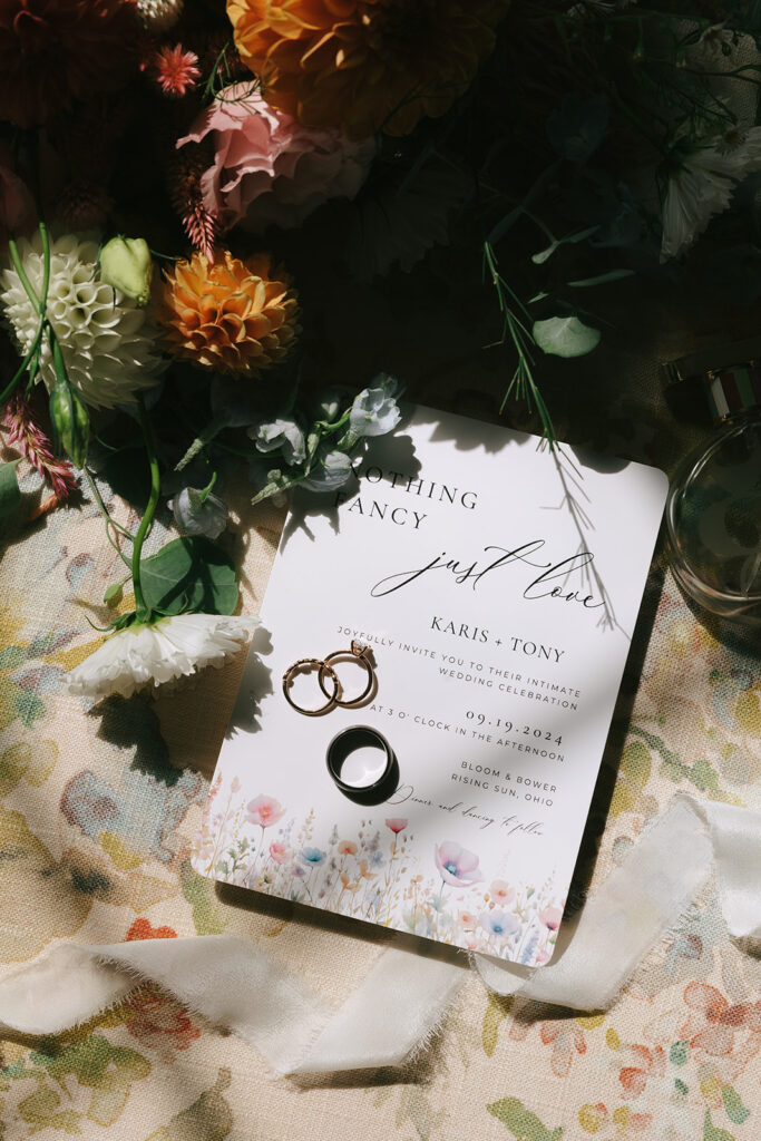 The couples wedding rings sit atop their wildflower themed invitations