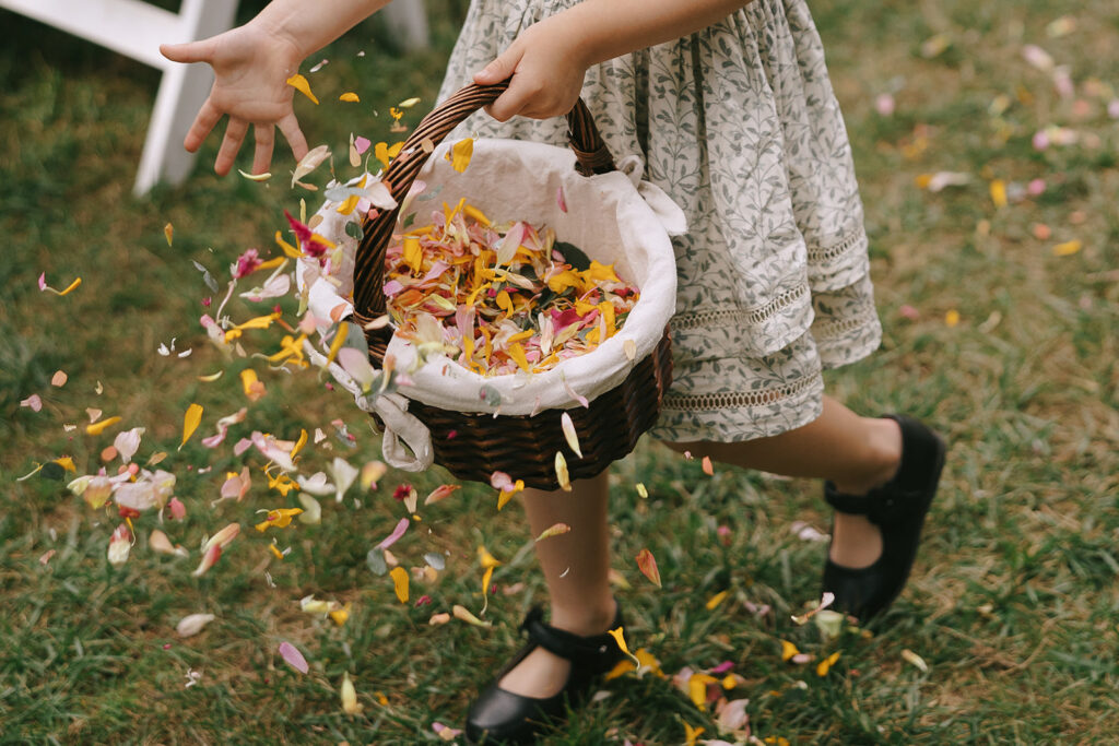 A flower girl tosses dried wildflower petals during Karis and Tony's wedding at Bloom and Bower