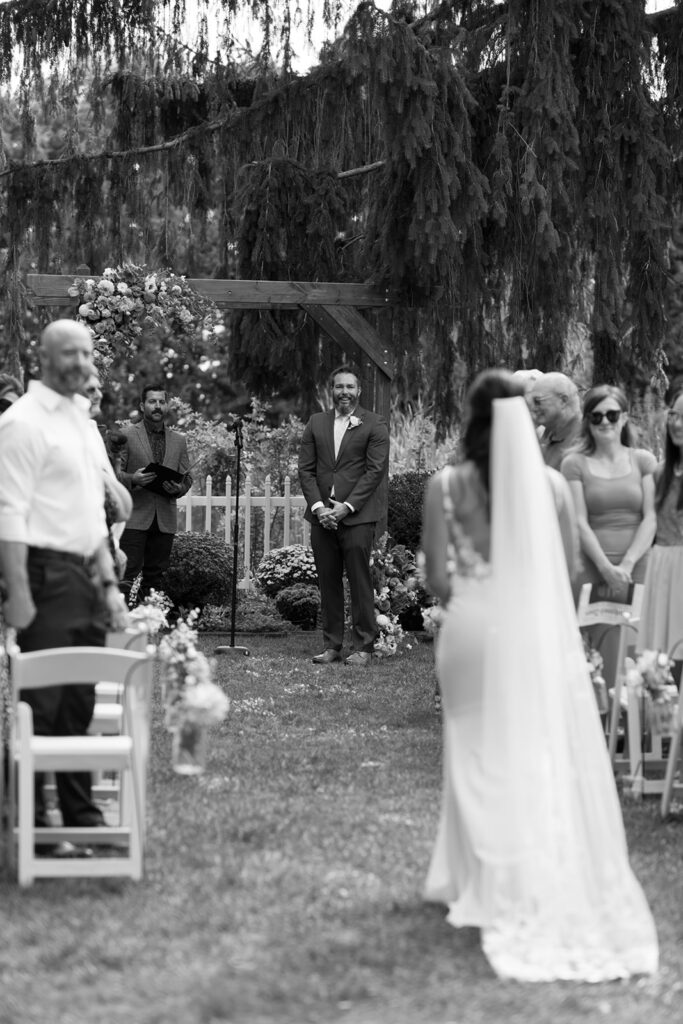 Tony watches as his bride comes down the aisle at Bloom and Bower, carrying her wildflower bouquet and wearing a custom bridal gown