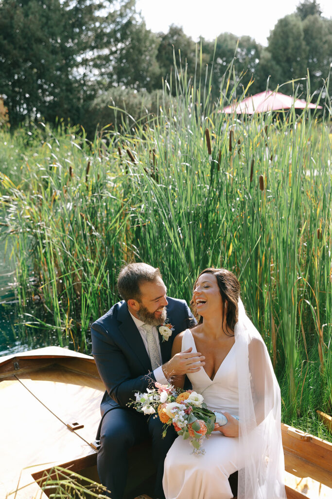 Karis laughs at something her groom says while sitting in the canoe at Bloom and Bower