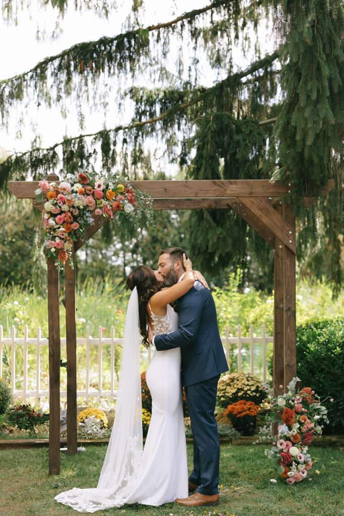 Karis and Tony share their first kiss under the wildflower arch at Bloom and Bower