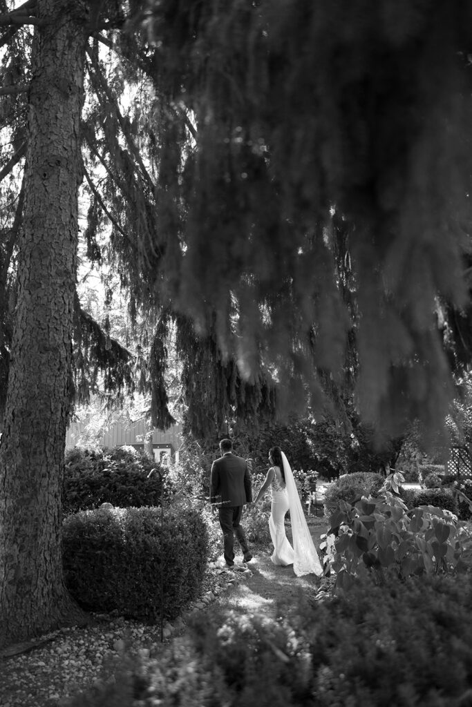 Karis and Tony walk around a tree in the gardens at Bloom and Bower