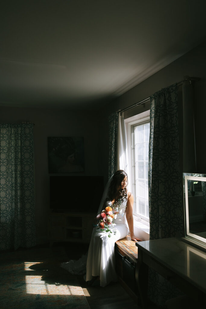 Karis sits while looking out the window at the grounds of Bloom and Bower while holding her wildflower bouquet