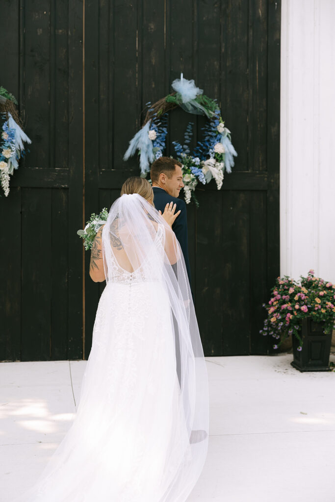 Bride walking away to the groom during their first look, her veil flowing behind her, with the groom looking back over his shoulder.