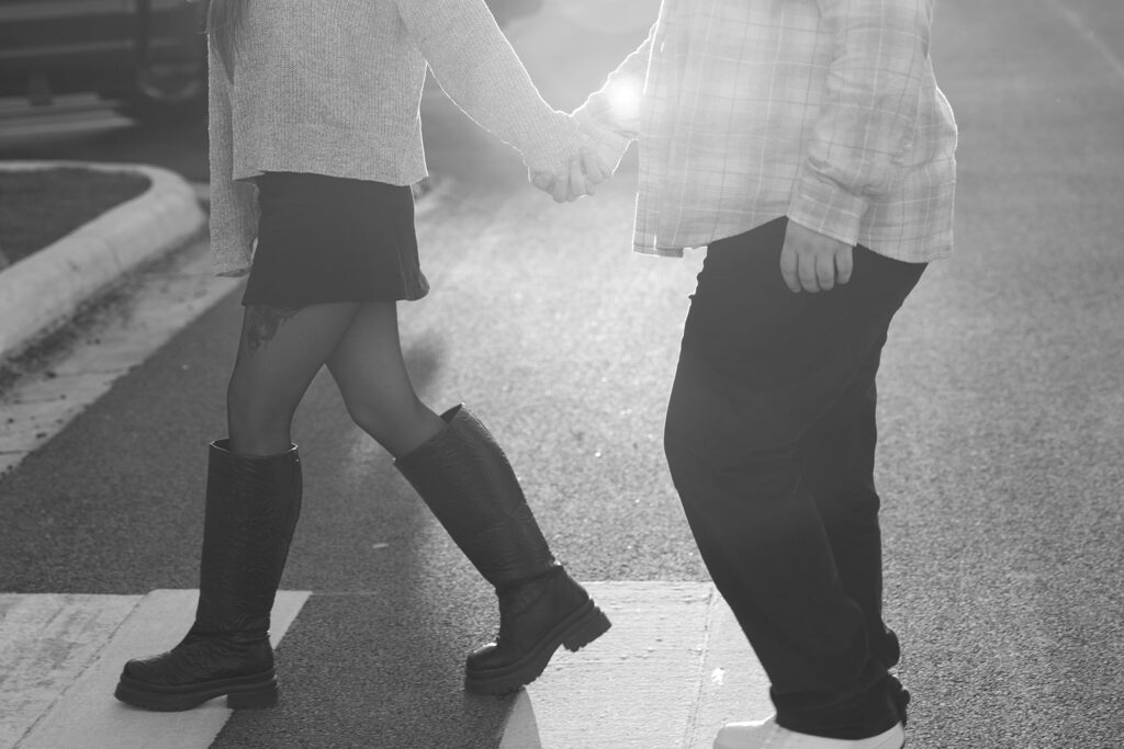 Black and white street photo of a newly engaged couple outside a historic building, blending timeless style with modern romance.