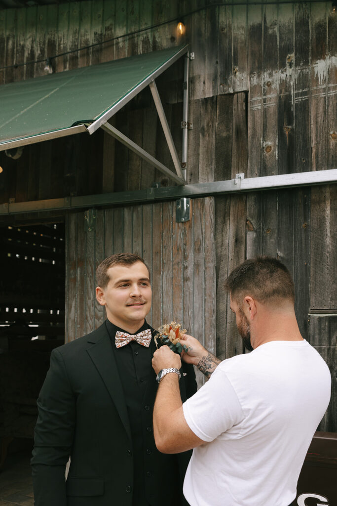Groom getting his tie adjusted while getting ready for his wedding