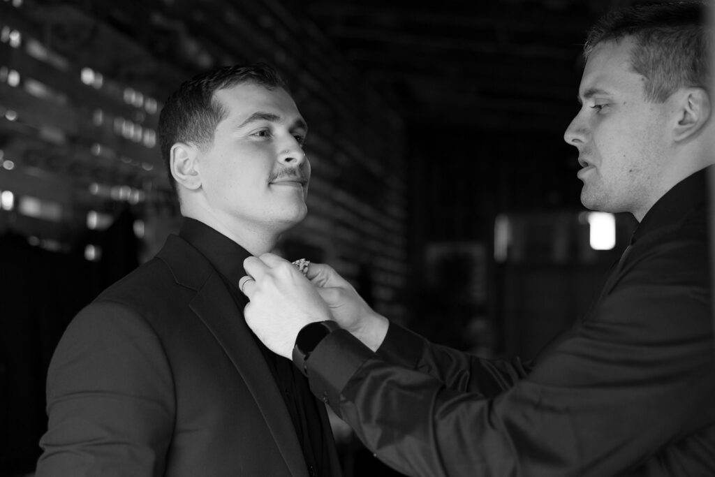 Groom getting his tie adjusted at the same location as the bride