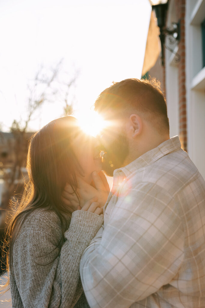 Engaged couple standing at the doorway of a historic building, holding hands in golden light, urban engagement photo idea for city lovers.
