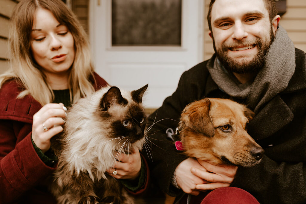 Couple sitting on their front porch including their dog in engagement photos with cozy, at-home vibes