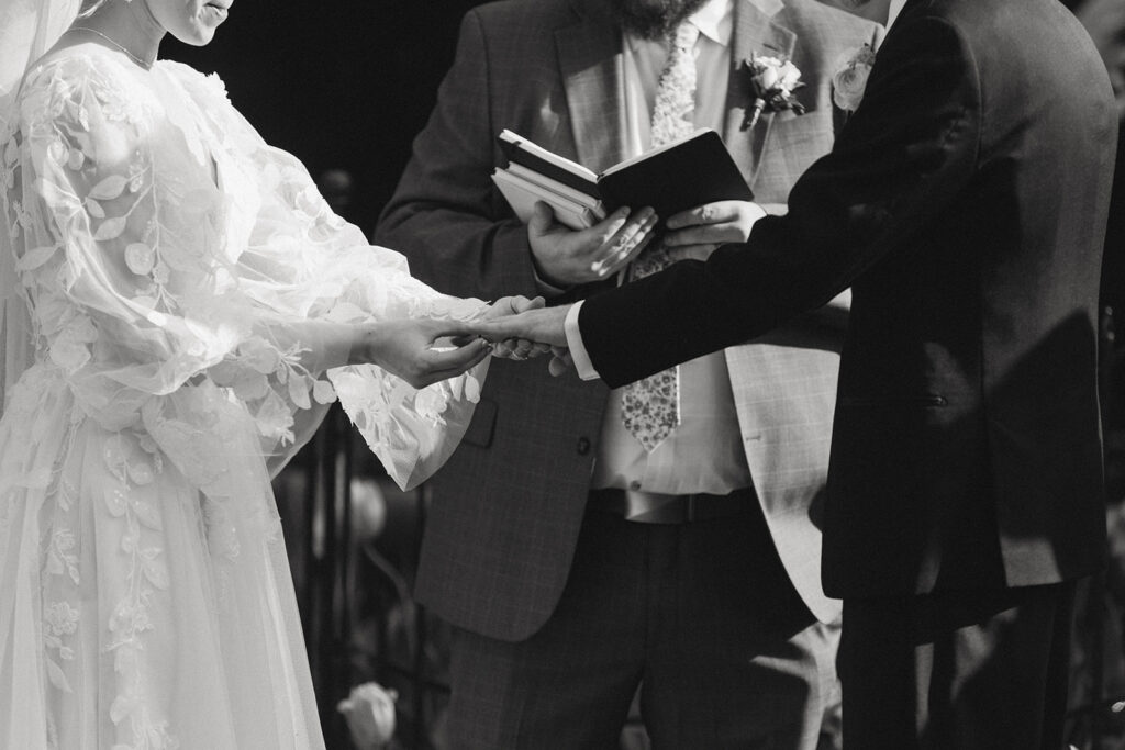 Bride slipping the ring onto the groom’s finger during the ceremony, a tender moment after overcoming prewedding jitters


