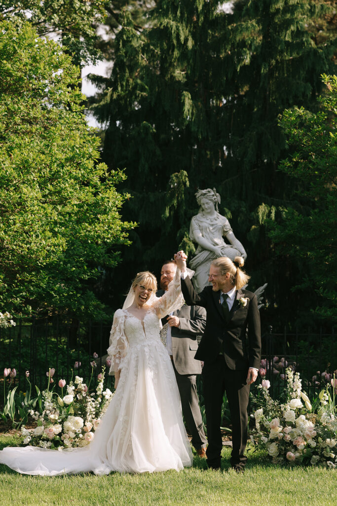 Bride and groom holding hands triumphantly after their first kiss, celebrating love and letting go of prewedding nerves.

