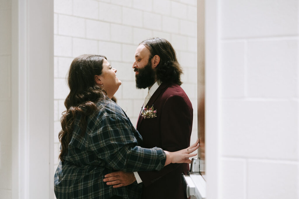 Bride in plaid shirt sharing a private first look with groom in burgundy suit, intimate and relaxed moment included in tips for the morning of your wedding.