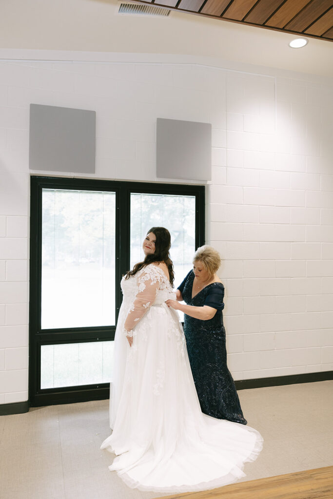 ride smiling as her mom helps zip her lace gown, a joyful candid that highlights support and organization in tips for the morning of your wedding.