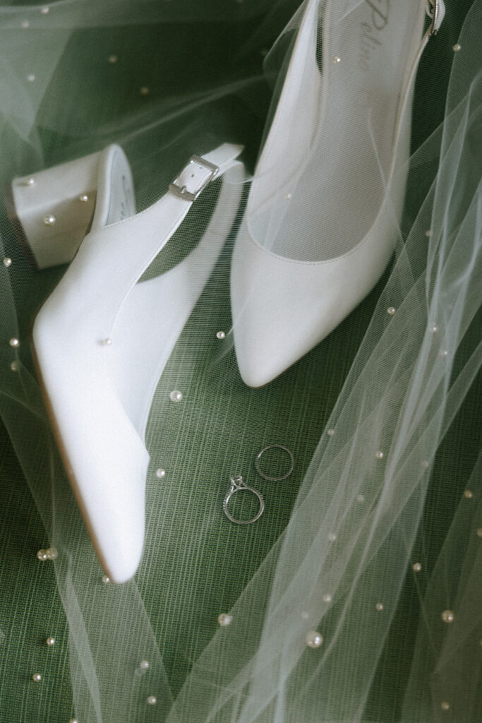 wedding day timeline details showing bridal shoes styled on a beaded veil with wedding rings