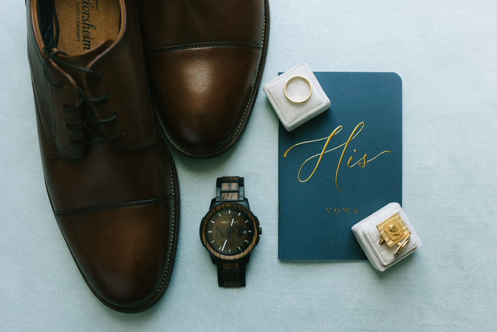 A flat lay of bridal heels, a floral invitation, a white rose, perfume, gold jewelry, and a vintage tray with a pink ring box. Wedding accessories and stationery often purchased during Black Friday wedding deals.

best Black Friday wedding deals