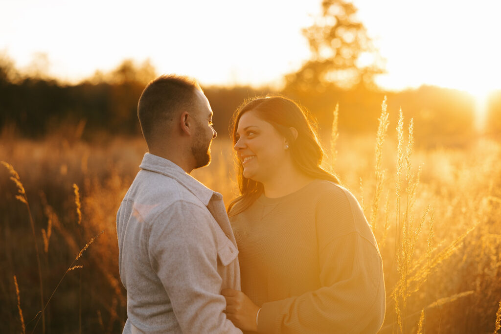 Engaged couple sharing a quiet moment in a golden field during sunset in Northwest Ohio