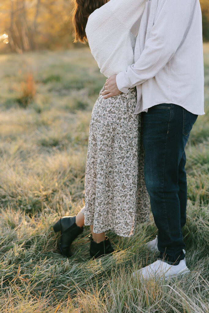 Engaged couple standing close together in a grassy field during a fall engagement session in Northwest Ohio