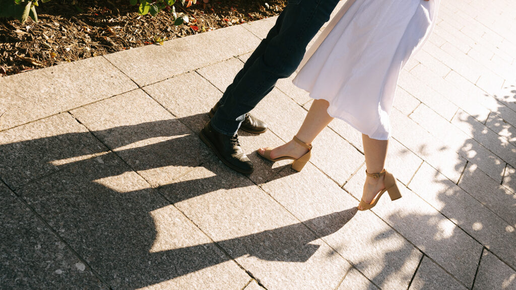 A man and a woman standing on a brick sidewalk.