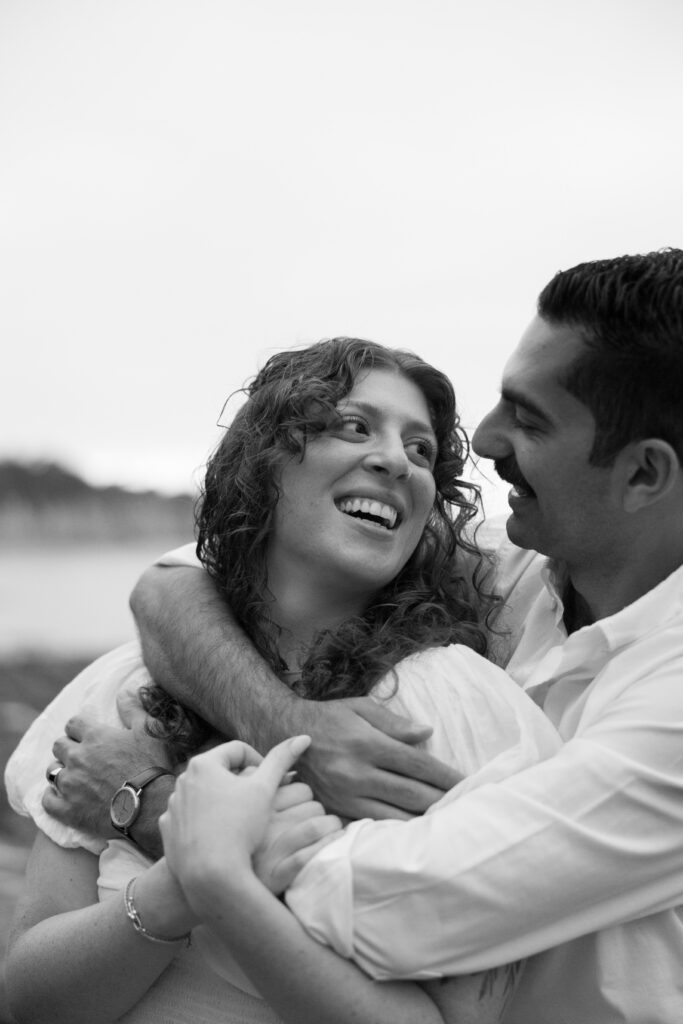 Toledo waterfront wedding portraits featuring the beach with a couple looking at each other and smiling. 
