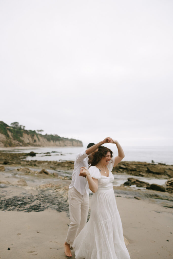 Toledo waterfront wedding portraits featuring the beach with a woman being twirled by a man.