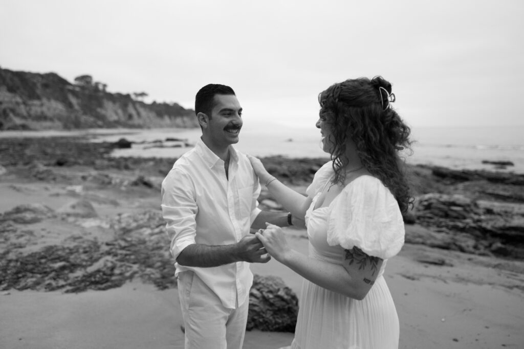 Toledo waterfront wedding portraits featuring the beach with a couple looking at each other and smiling.