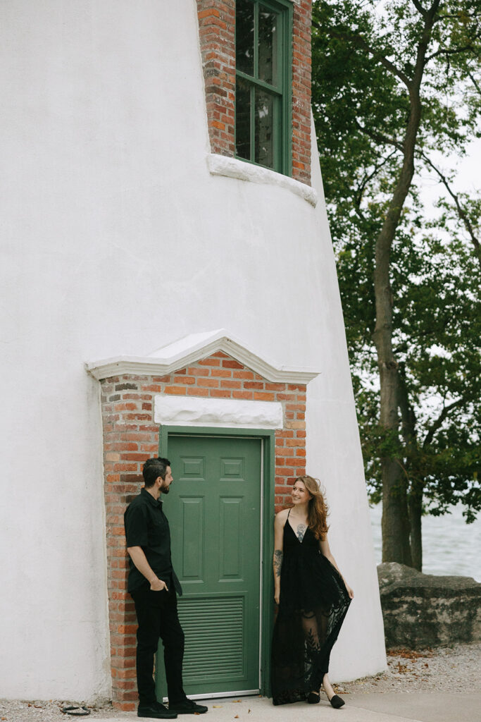 Engaged couple on the beach at a lighthouse.