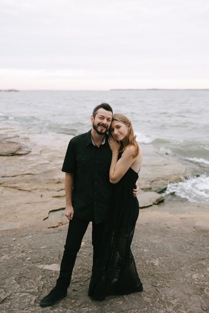 Woman and man on the beach smiling at the camera while the photographer gives advice for engaged couples.