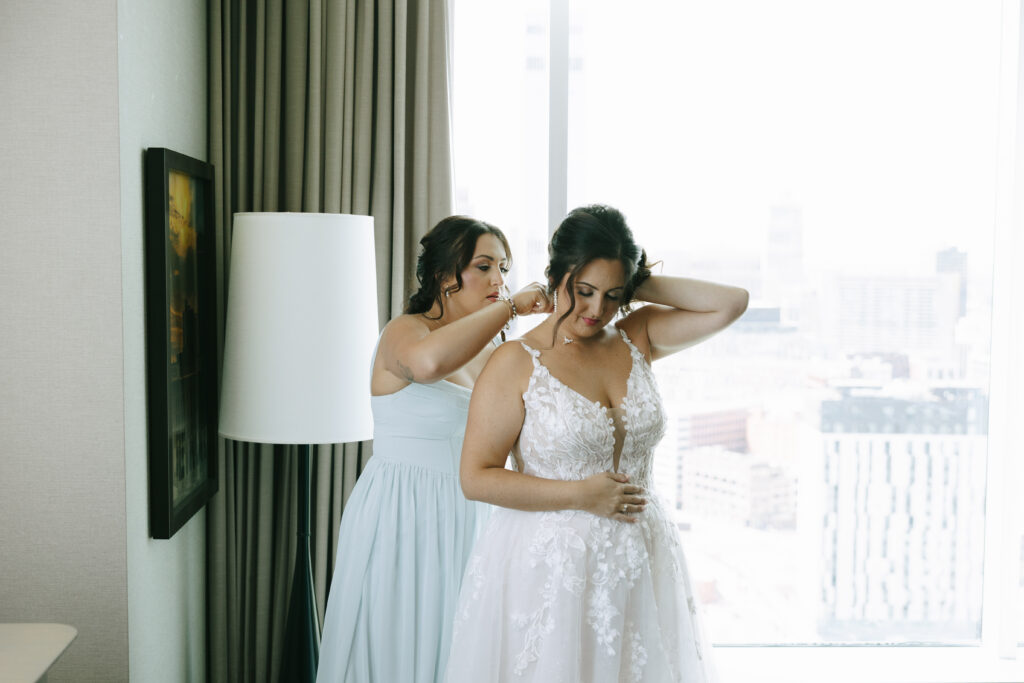 Getting ready photos taken by an Ohio photographer of a woman helping a bride with her necklace.