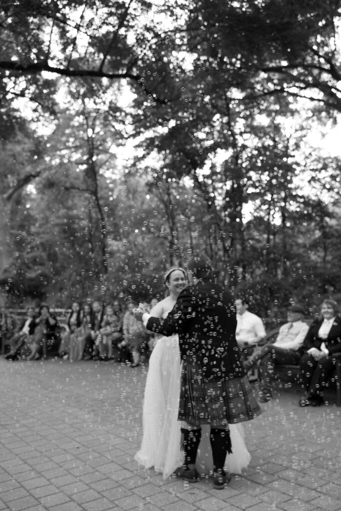 Candid wedding photo of a bride and groom dancing in bubbles.