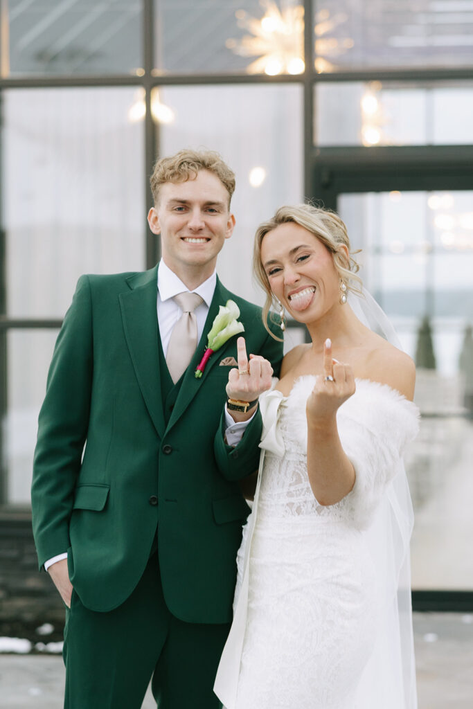 Bride and groom sharing a playful, candid moment on their wedding day, groom in green suit