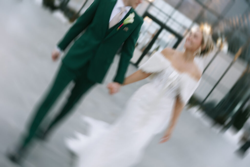 Groom in green suit walking with bride outdoors on wedding day