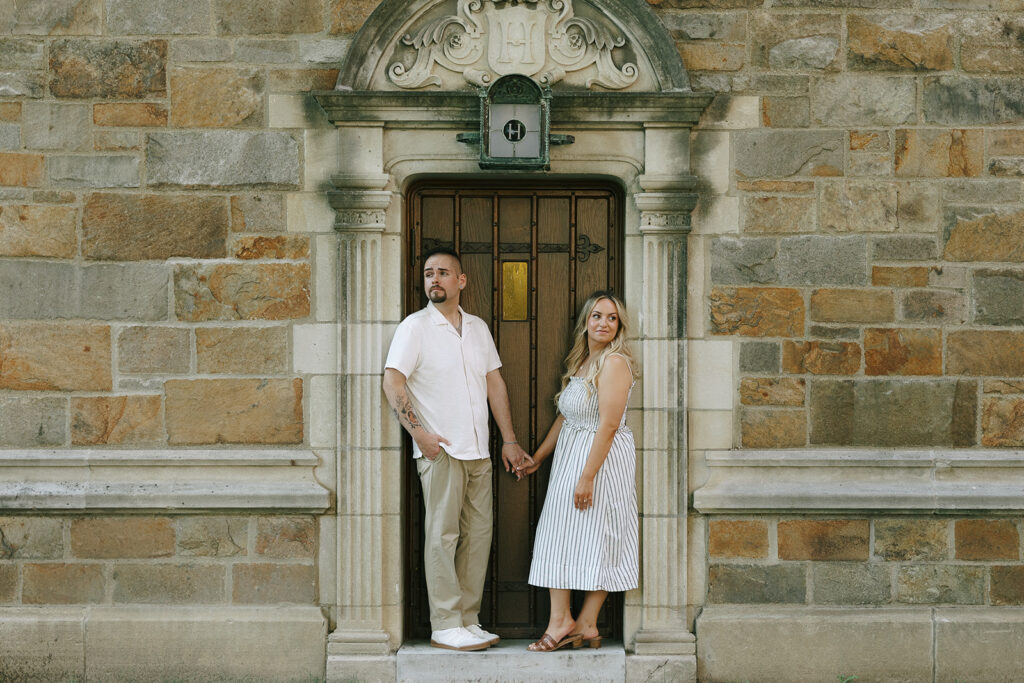Engaged couple embracing in front of a stone archway, an example of engagement photos used for wall art