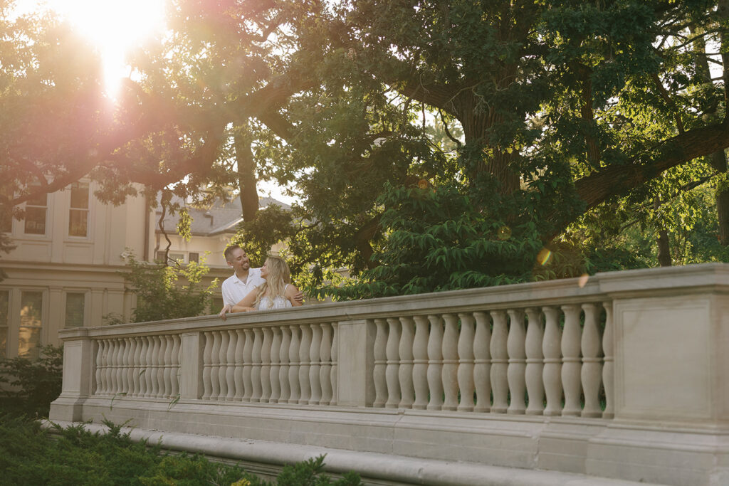 Engaged couple standing on a stone terrace at golden hour
