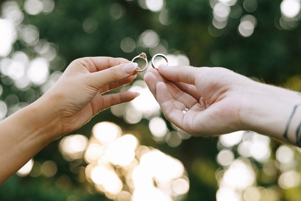 Close-up of hands holding wedding rings with soft bokeh background